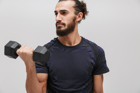 Image of young strong man in sportswear doing exercise with dumbbell