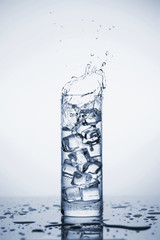 Clear mineral water splashes in a glass with ice.