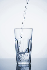 Clear mineral water is poured into a glass with ice.