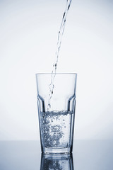Clear mineral water is poured into a glass with ice.