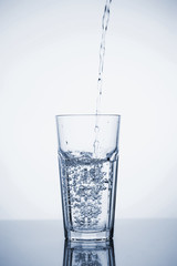 Clear mineral water is poured into a glass with ice.