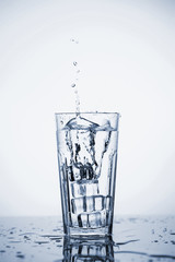Clear mineral water splashes in a glass with ice.