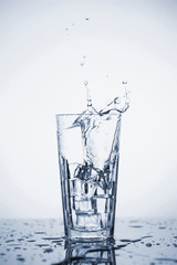 Clear mineral water splashes in a glass with ice.