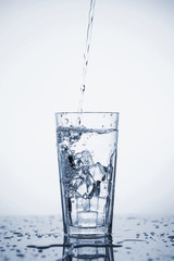 Clear mineral water is poured into a glass with ice.