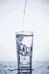 Clear mineral water is poured into a glass with ice.