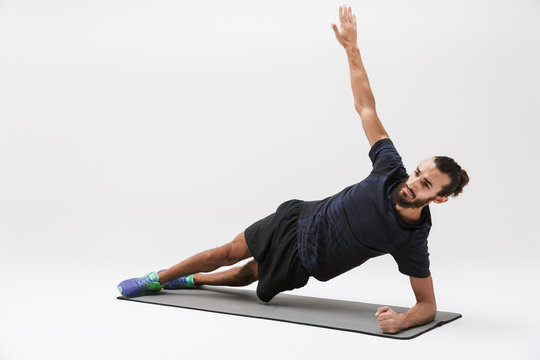 Image of active sportsman in tracksuit doing workout on yoga mat