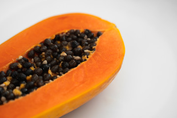 Half cut ripe papaya with seed on a white plate. Slices of sweet papaya with a white background. Halved papayas. Healthy exotic fruits. Vegetarian food.