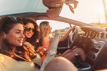 Three female friends enjoying road trip traveling at vacation in the car.