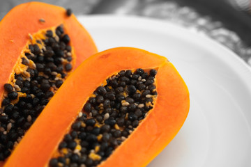 Half cut ripe papaya with seed on a white plate. Slices of sweet papaya with a white background....