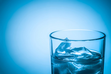 glass cup with clear water and ice cubes on a dark blue background, with space for your text