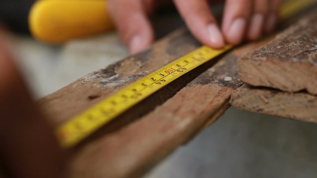Woodworker masuring lumber wood and marking, prepare to cut to building a wooden table
