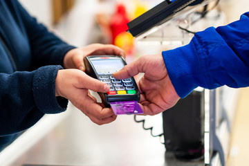 Close up of using credit card pos terminal to pay. Hands entering the password of creditcard for...
