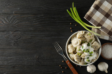 Bowl with dumplings, towel, fork and spices on wooden background, top view