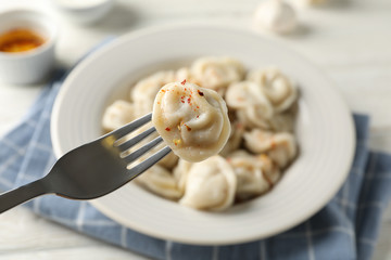 Fork with dumpling. Plate with dumplings and towel on white background, close up