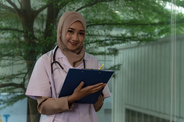 Asian muslim doctor work ,meeting hospitle.consult together.hold file in hand,smiling.