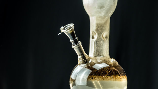 Close-up of dirty water bong on black background. Smoking cannabis with water pipe.