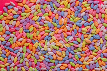 Fototapeta na wymiar Sunflower seeds in colored glaze lie on a pink background. Flat lay, copy space, top view.