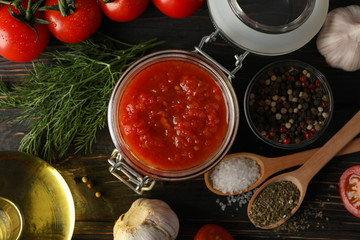 Chilli sauce, garlic, cherry tomatoes, olive oil, spices on wooden background, close up. Top view