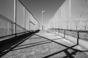 Outdoor overpass ramp walkway with chain link fence. Industrial design and detail.