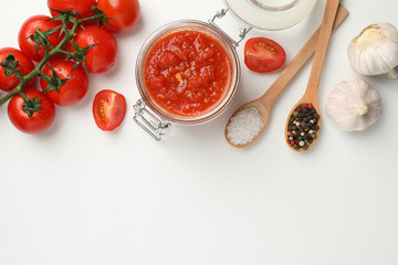 Chili sauce in glass jar and ingredients on white background, space for text. Top view