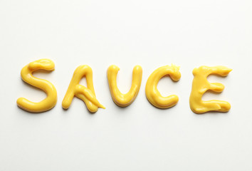 Inscription SAUCE made of sauce on white background, top view