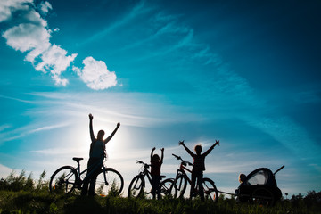 Happy mother with kids biking at sunset, family enjoy bike ride