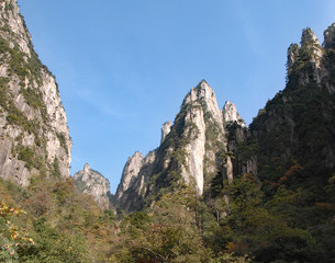 Fototapeta na wymiar Huangshan Mountain in Anhui Province, China. View of mountain peaks, cliffs and trees at the lower part of West Sea or Xi Hai canyon on Huangshan. From the West Sea path on Huangshan Mountain, China.