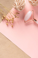 Pink Gua Sha massage tool and dry flowers on a pink background, top view, free space for text. Rose Quartz jade roller. Facial skin care at home, anti-aging and lifting therapy, copy space.	