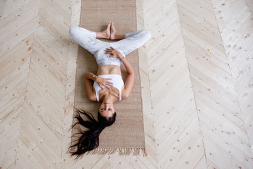 Top view of beautiful pacified young woman yoga instructor in sportswear doing Supta Baddha...