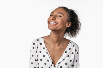 African american woman laughing and closing eyes with pleasure isolated over white background