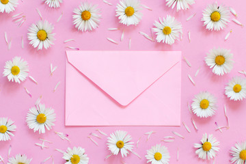 White daisies and an envelope on a light pink background