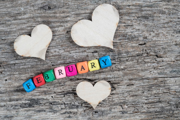 colorful cube calendar and hearts on wooden background for february