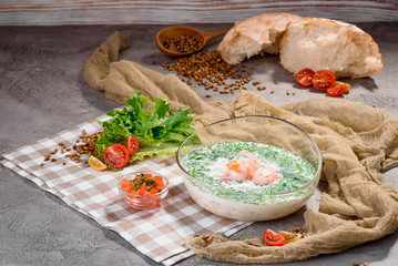 Cold soup with shrimp and cream in a beautiful transparent bowl on a light concrete background in a beautiful composition with fresh vegetables. Close-up. Space
