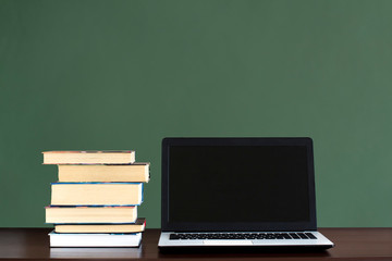 white and black laptop and stack of books on a dark wooden table