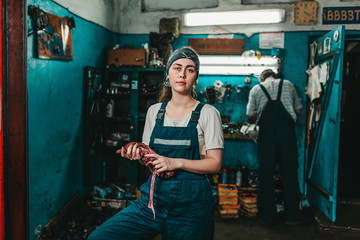 Gender equality. Portrait of a young strong woman in uniform working in a workshop, which wipes his...