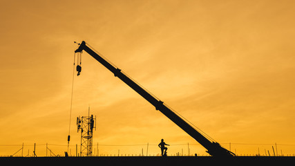 Silhouette sunset construction working and machinery crane hoisting cement mortar mixer bucket...