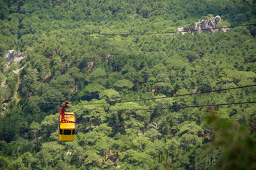 Yellow cable car. Funicular in mountains. Green forest. View from above.