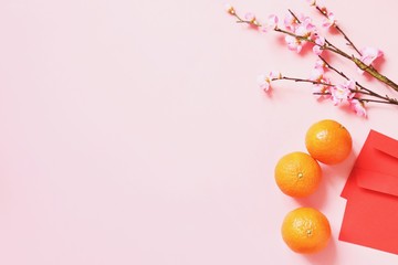 Flat lay Chinese New Year photo. Oriental traditions. Pink flowers, mandarins and red envelopes....