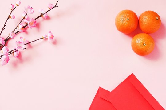 Chinese New Year background. Flat lay pink sakura, mandarins and red pockets for money. Mockup