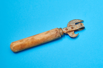Old rusty can opener on a blue background.