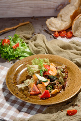 Healthy salad of fresh tomatoes, sweet pepper cucumbers, lettuce, sauce on yellow plate on concrete background, decorated with checkered napkin with fresh vegetables and beautiful bread. Space