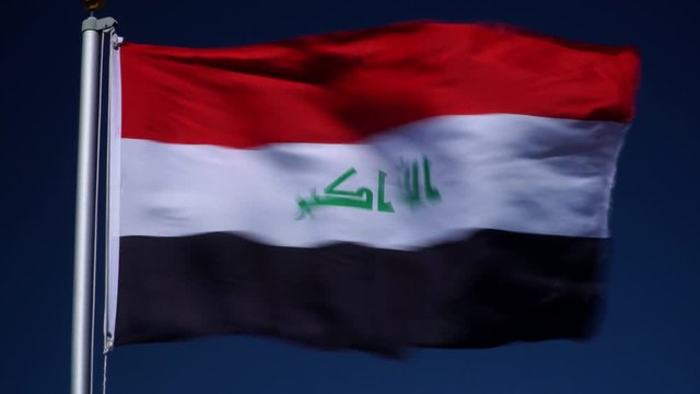 Iraq Flag flying in the wind outdoors with Blue sky behind - Iraqi flag on flagpole.
