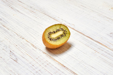 Half kiwi on a light wooden background.