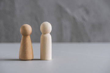Wooden people man and woman against the background of a gray concrete wall. The concept of family, friendship, relationships.