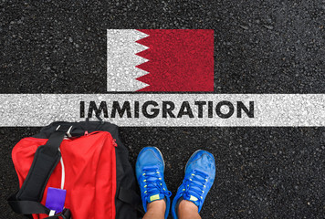 Man in shoes with bag standing next to line with word IMMIGRATION and flag of Bahrain on asphalt...