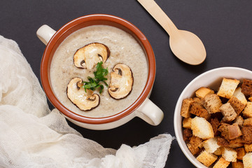Cream soup with mushrooms in porcelain bowl on kitchen towel.