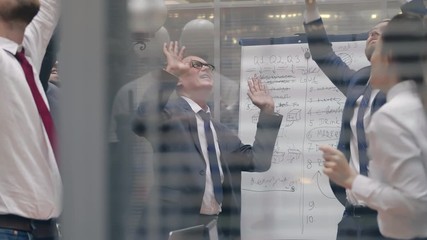Happy business managers wearing suits and ties dancing in the office meeting room. Colleagues are cheering celebrate successful contract deal. Diverse motivated business people have fun party holidays