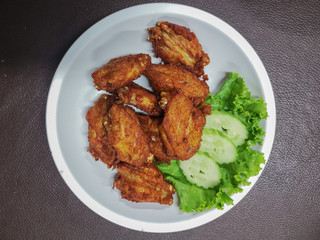 Close up of Frying chicken in white dish on gray table.