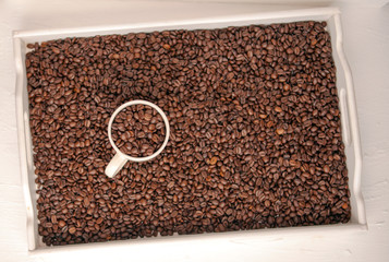 white cup of coffee with coffee grain on grain background. coffee beans top view. Coffee cup and beans view from above. Coffee close-up brown beans texture background. Overflowing beans.