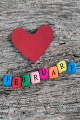 colorful cube calendar and heart on wooden background for February